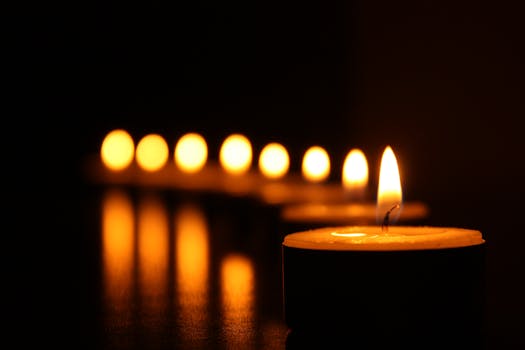 A close-up view of tealight candles reflecting a warm glow in the dark.